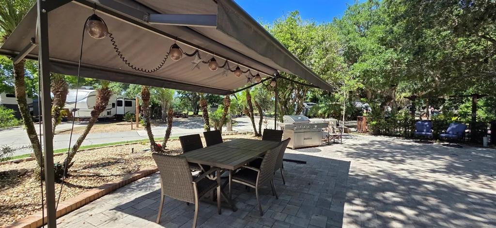 An outdoor patio features a dining set under a retractable awning and a stainless grill — 185 APPALOOSA TRAIL, RIVER RANCH, FL