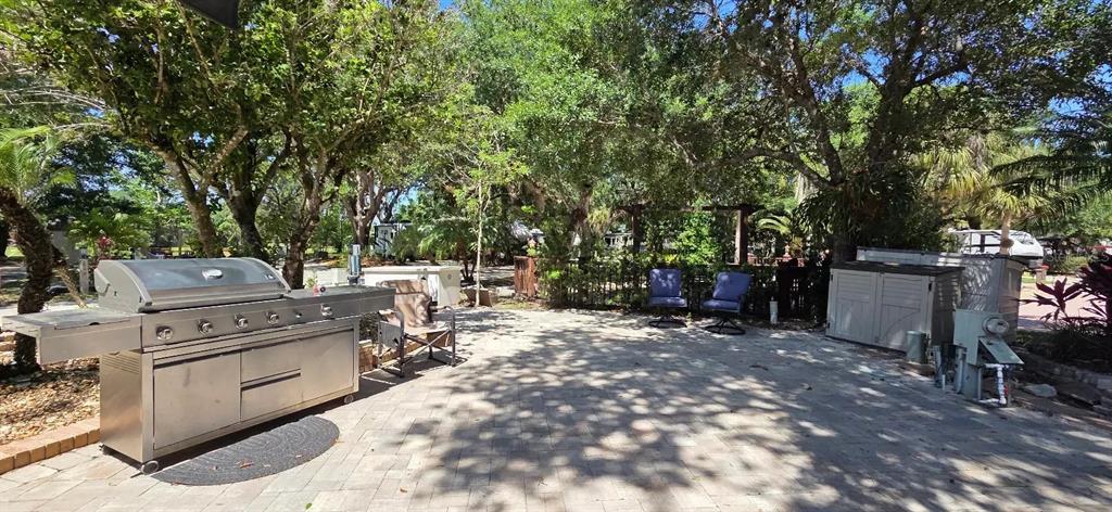 A paved outdoor patio features a stainless steel grill, two chairs, and storage units — 185 APPALOOSA TRAIL, RIVER RANCH, FL