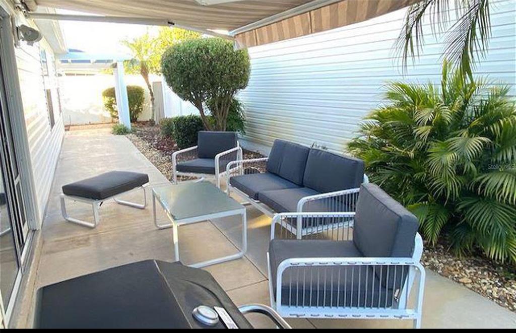 A patio features a white metal sofa set, a coffee table, and a grill — 1228 ESTILL AVENUE, THE VILLAGES, FL