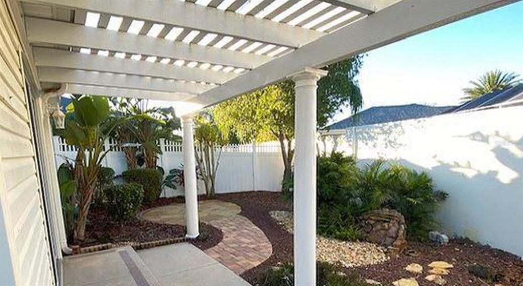 A patio with a white pergola, columns, and a brick walkway in a fenced backyard — 1228 ESTILL AVENUE, THE VILLAGES, FL
