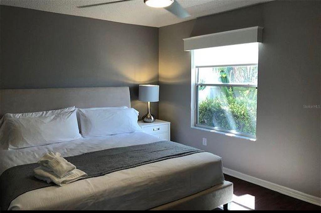 A bedroom features a bed with white bedding, a gray runner, and a bedside lamp — 1228 ESTILL AVENUE, THE VILLAGES, FL