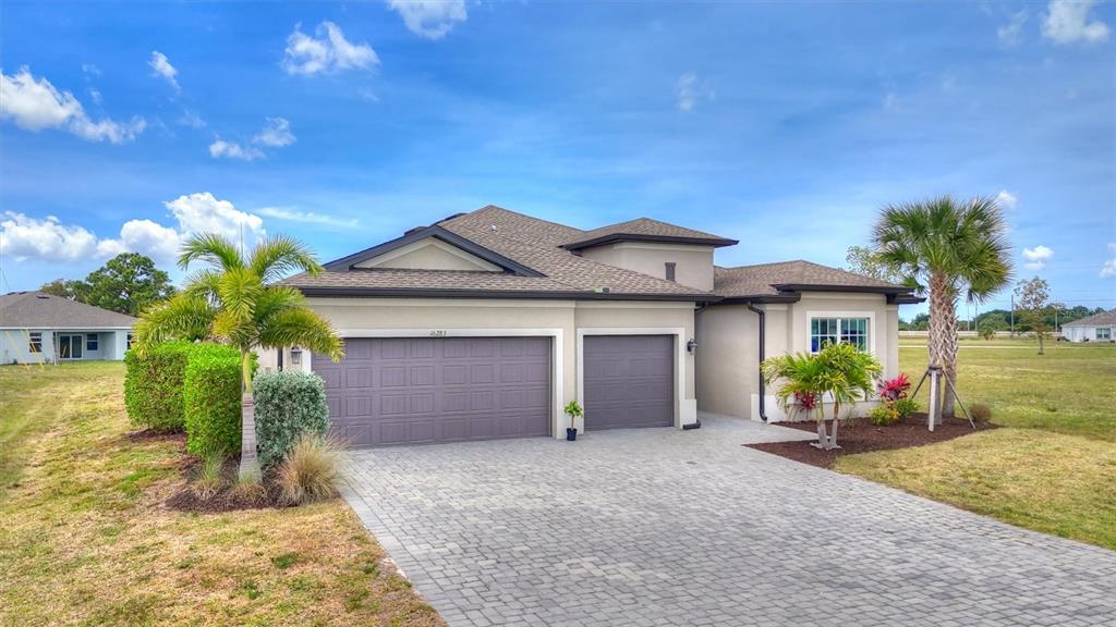A single-story house with a paved driveway, two garage doors, and palm trees in front — 16283 ALCIRA CIRCLE, PUNTA GORDA, FL