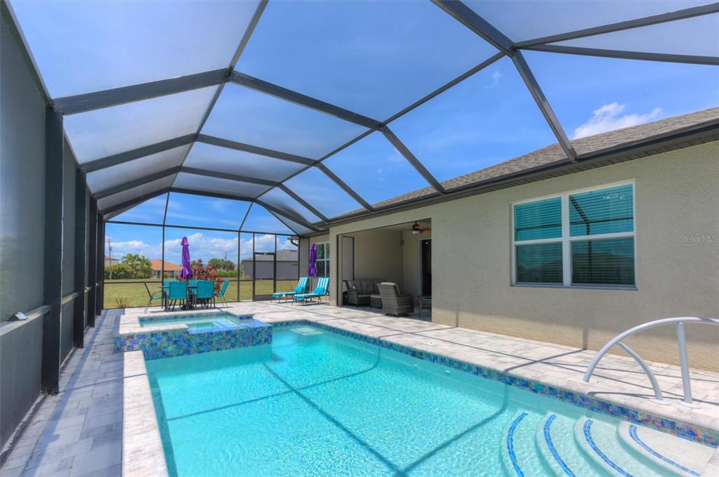 A screened-in patio features a swimming pool, a raised hot tub, and outdoor furniture — 16283 ALCIRA CIRCLE, PUNTA GORDA, FL