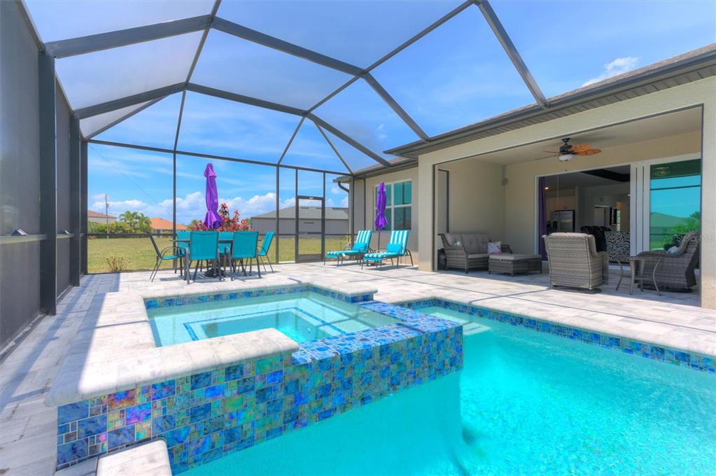 A screened-in patio features a tiled pool and spa with outdoor furniture under a lanai — 16283 ALCIRA CIRCLE, PUNTA GORDA, FL