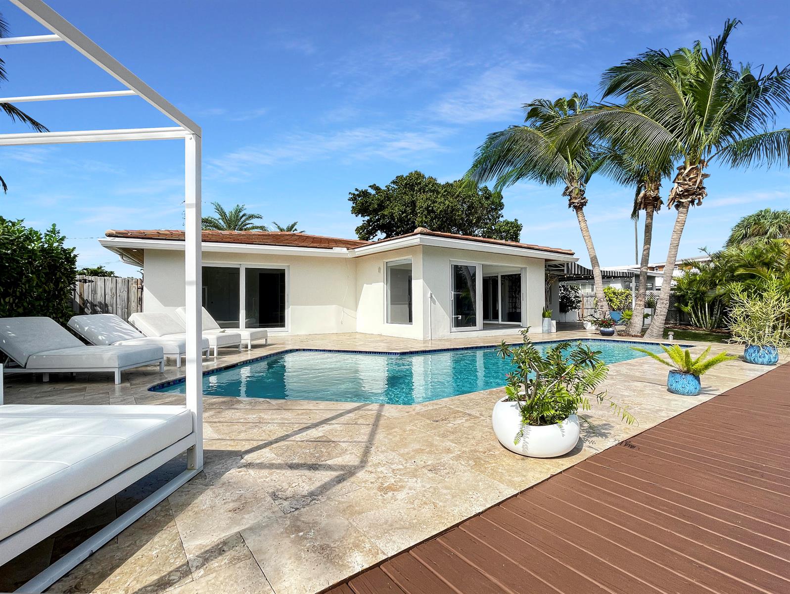 A swimming pool sits on a stone patio next to a house with palm trees — 2164 NE 25th Street, Wilton Manors FL 33305, WILTON MANORS, FL