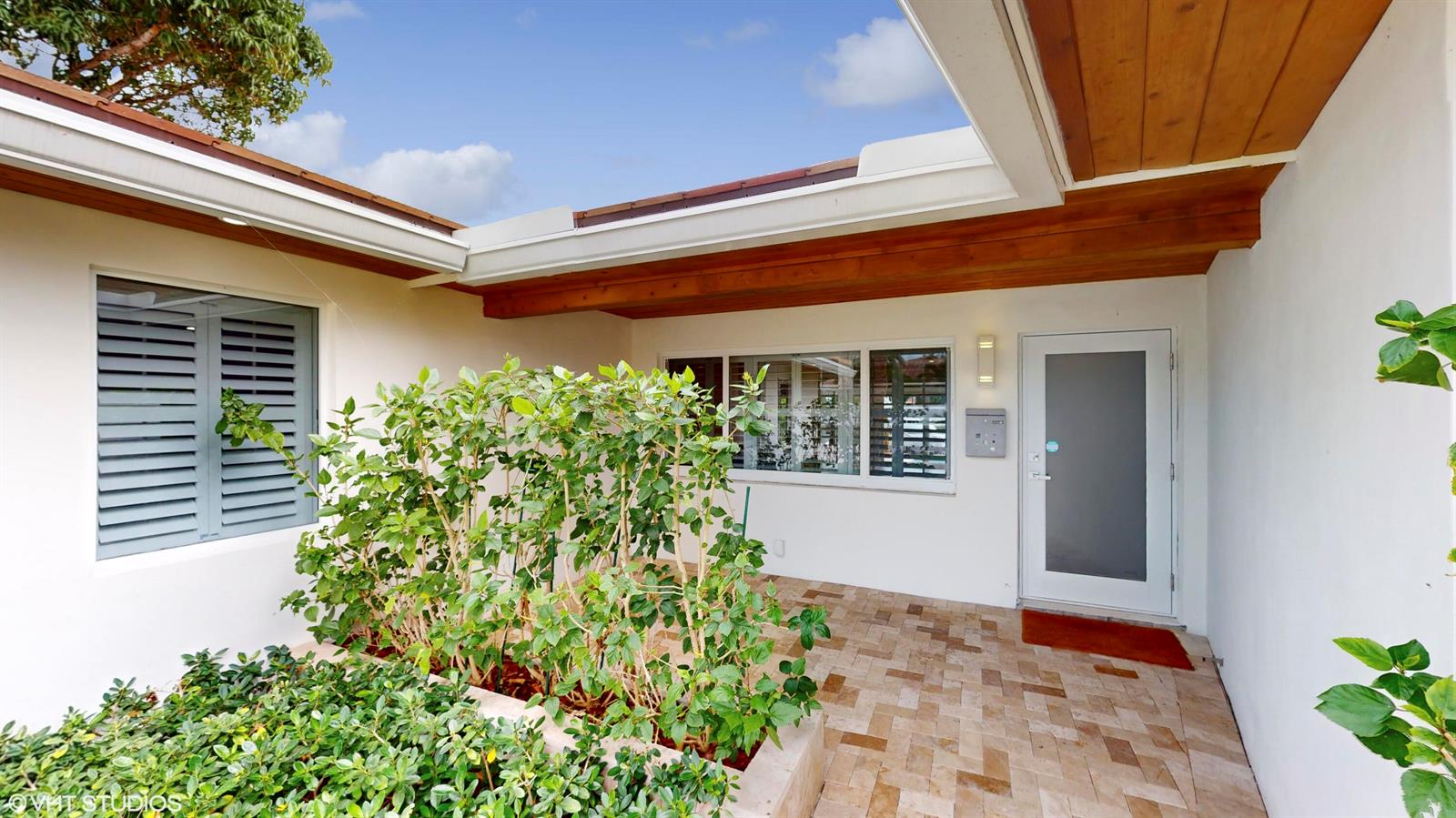 An outdoor entryway features a tiled patio, a planter with green shrubs, and a door — 2164 NE 25th Street, Wilton Manors FL 33305, WILTON MANORS, FL
