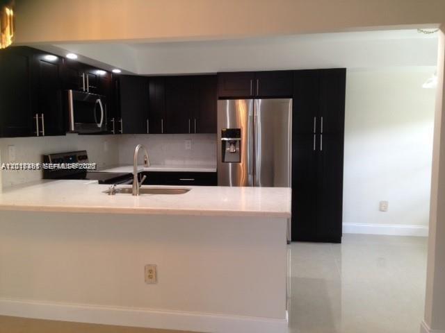 A kitchen with dark cabinets, stainless steel appliances, and a white countertop island — 451 NE 210th Cir Ter # 19, Miami FL 33179, MIAMI, FL