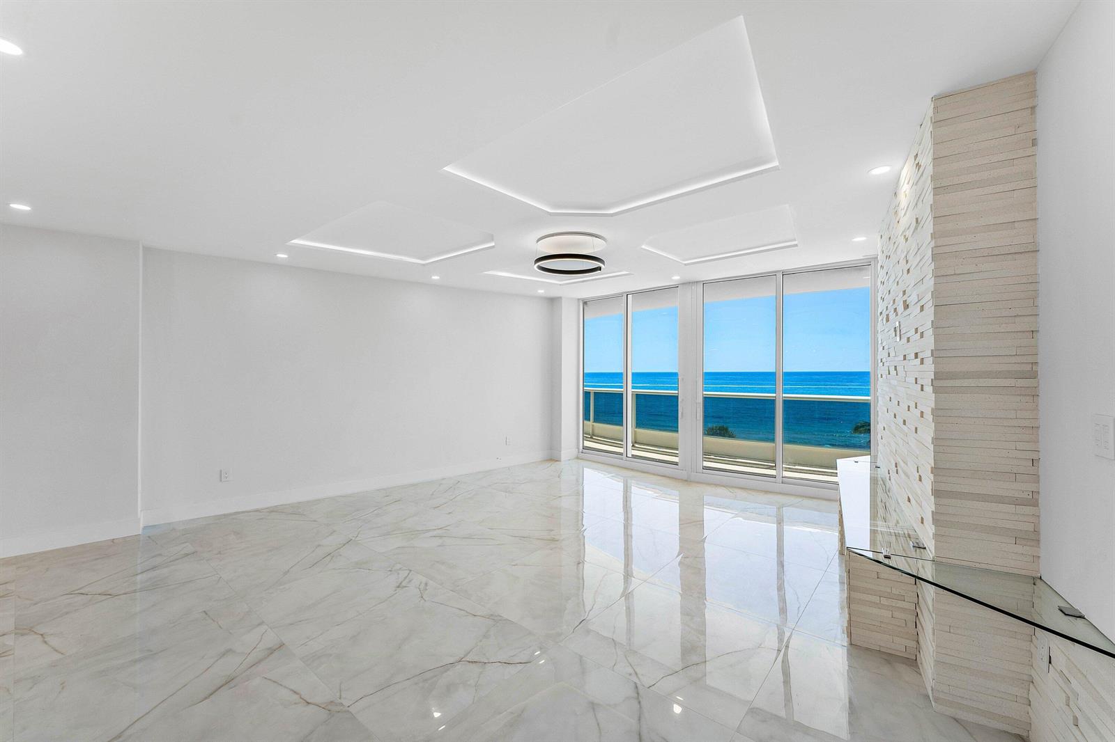 A bright, empty living room features white marble floors, a tray ceiling, and ocean views — 700 S Ocean Boulevard # 504, Boca Raton FL 33432, BOCA RATON, FL