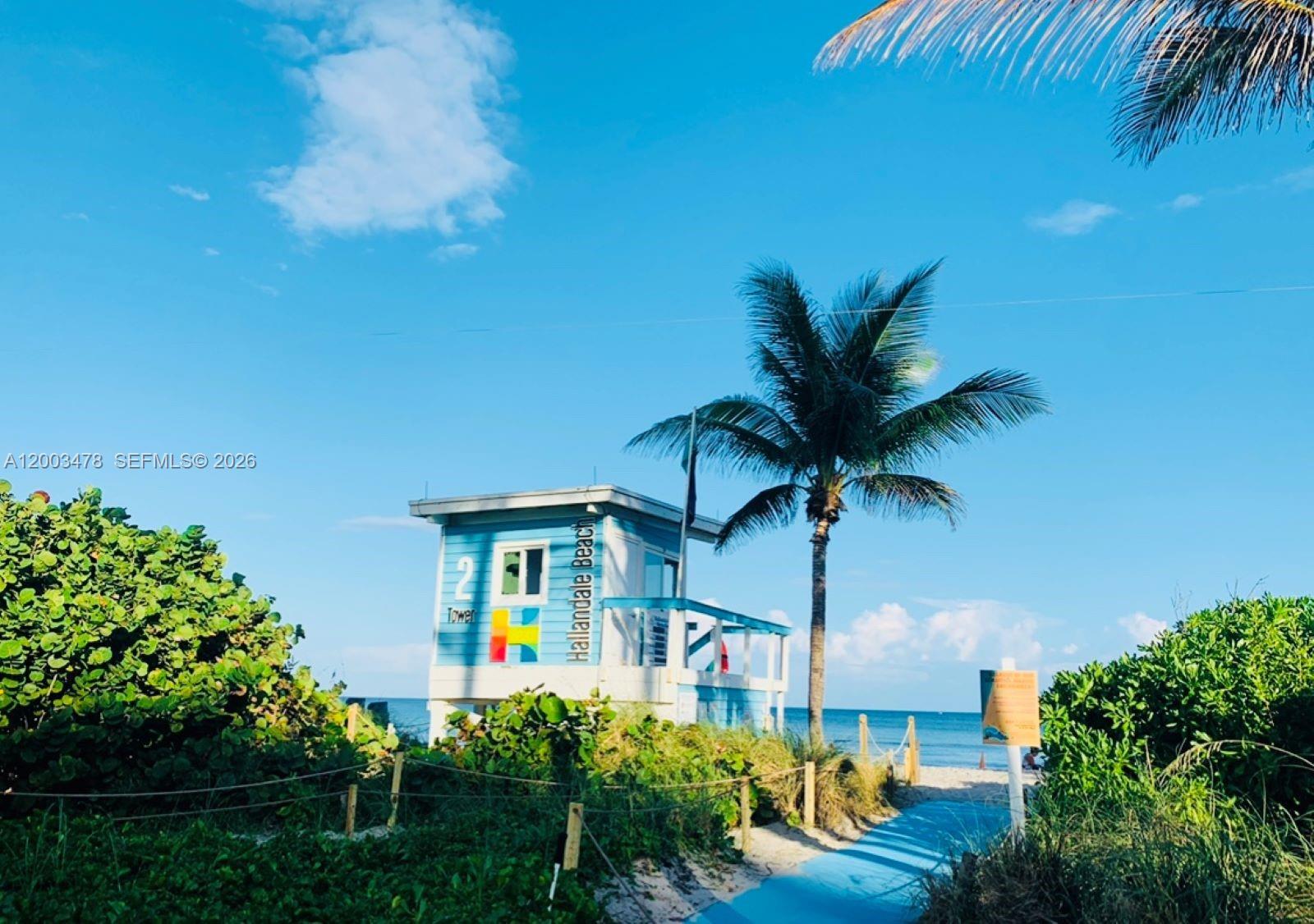 A lifeguard tower stands on a sandy beach path surrounded by lush green vegetation — 215 SE 3rd Ave # 306C, Hallandale Beach FL 33009, HALLANDALE BEACH, FL