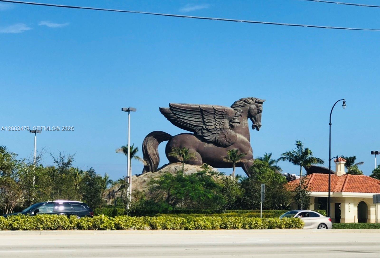 A large bronze Pegasus statue stands on a landscaped mound near a road — 215 SE 3rd Ave # 306C, Hallandale Beach FL 33009, HALLANDALE BEACH, FL