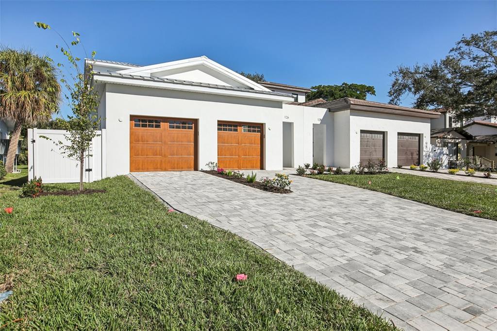 A covered patio overlooks a rectangular swimming pool with three water features and palm trees — 126 RICARDO WAY NE, ST PETERSBURG, FL
