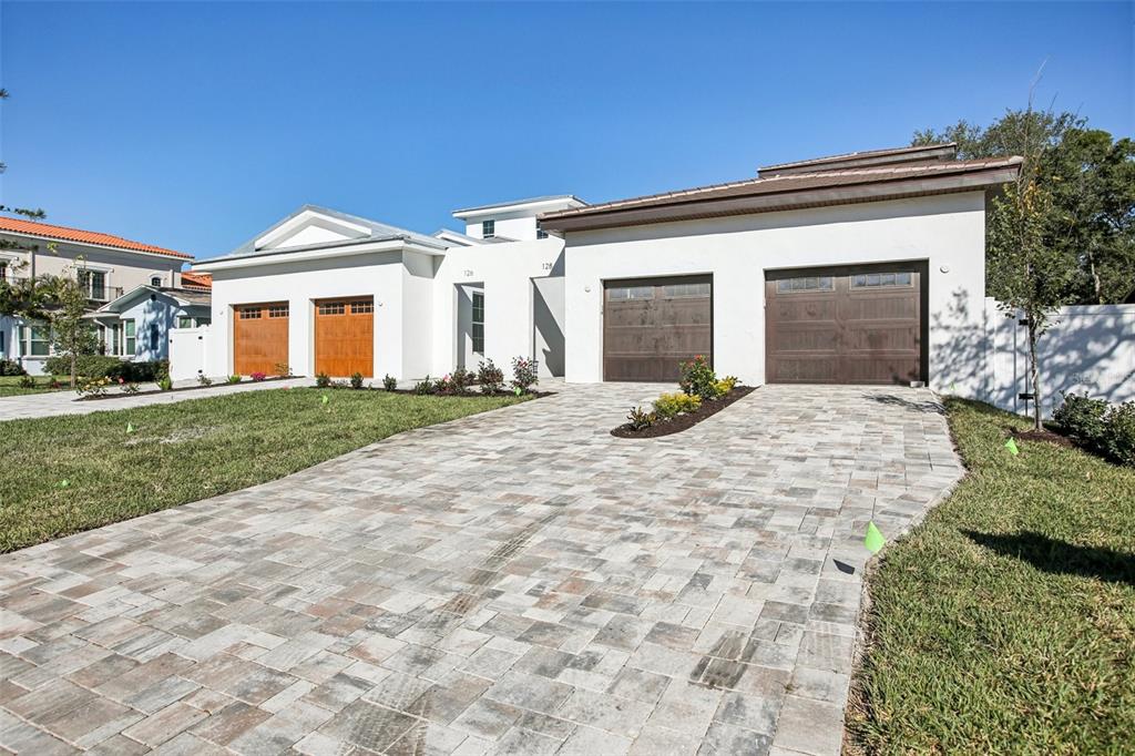 A modern white house exterior features a concrete patio with gray wicker outdoor furniture — 126 RICARDO WAY NE, ST PETERSBURG, FL