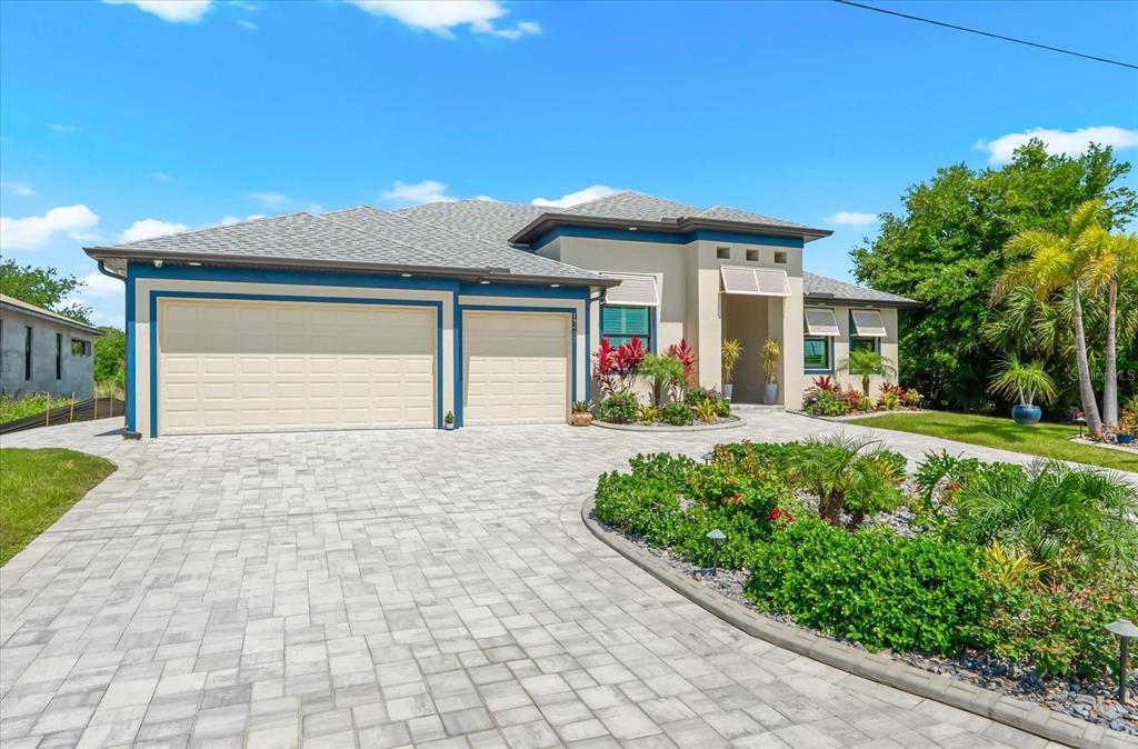 A single-story house with a three-car garage, paved driveway, and landscaped front yard — 13407 CHENILLE DRIVE, PORT CHARLOTTE, FL