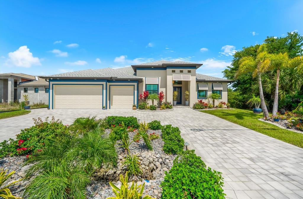 A single-story house with a three-car garage and a paved driveway under a blue sky — 13407 CHENILLE DRIVE, PORT CHARLOTTE, FL