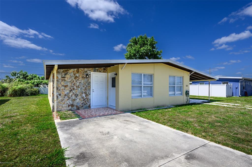 A single-story house with a stone facade, yellow siding, and a concrete driveway — 510 SHARON CIRCLE, PORT CHARLOTTE, FL