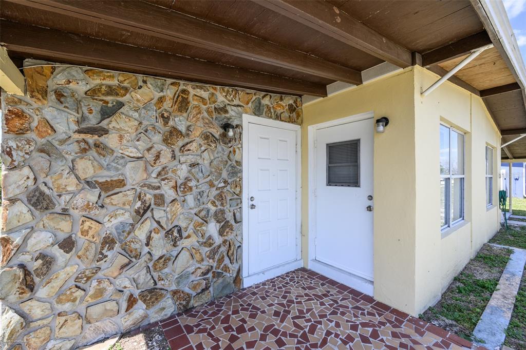 An exterior view of a house entrance with a stone wall and tiled patio — 510 SHARON CIRCLE, PORT CHARLOTTE, FL