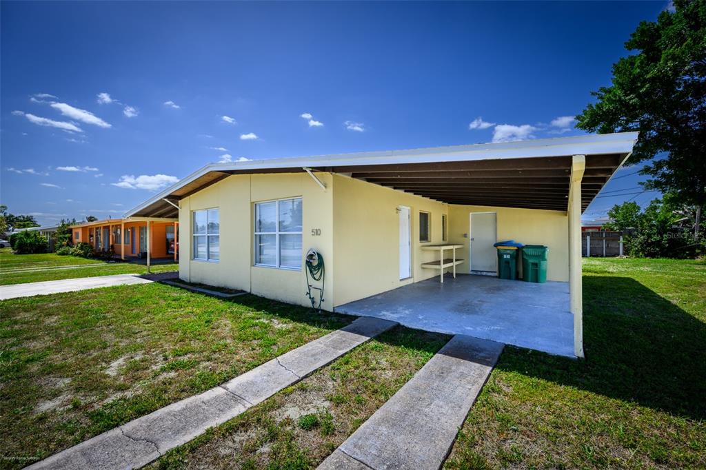 A yellow single-story house features a carport, a concrete driveway, and a grassy yard — 510 SHARON CIRCLE, PORT CHARLOTTE, FL