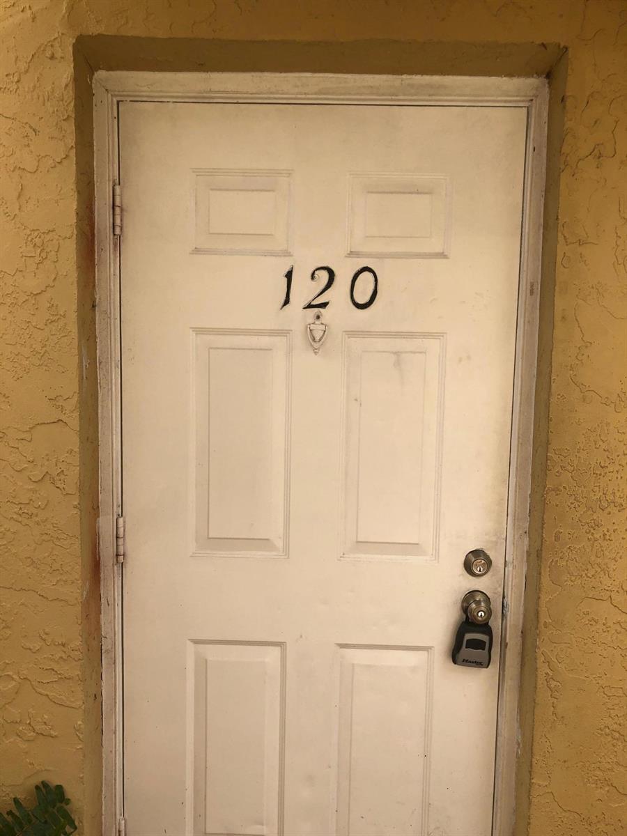 A white six-panel door labeled 120 with a lockbox attached to the handle — 6031 10th Avenue N # 120, FL 33463, FL