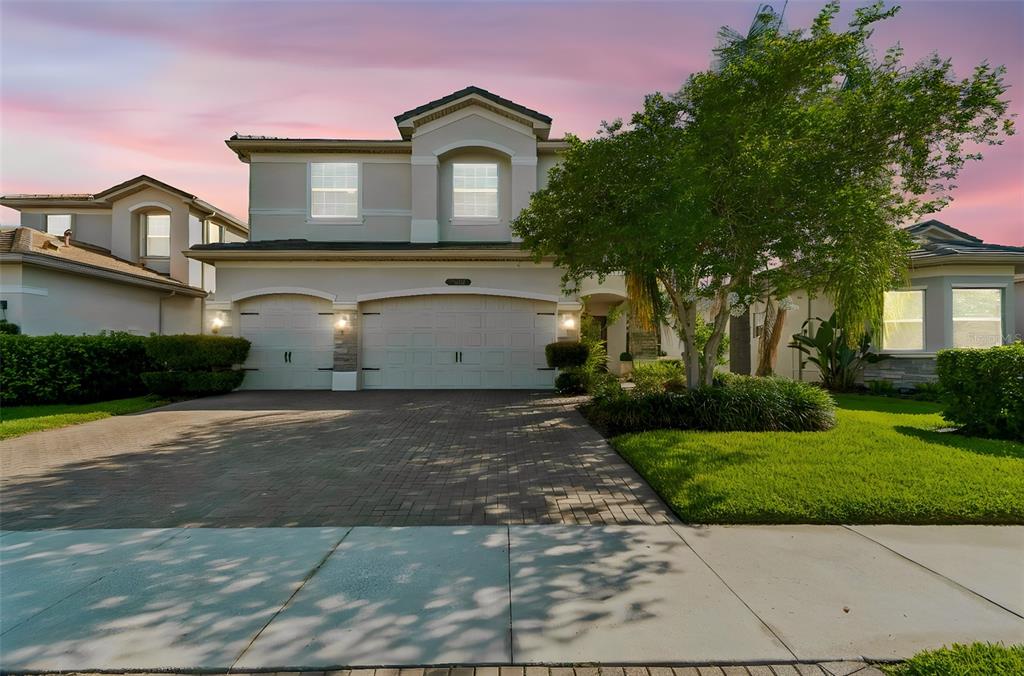 A two-story suburban house with a three-car garage, brick driveway, and manicured front lawn — 30229 SOUTHERNWOOD COURT, WESLEY CHAPEL, FL