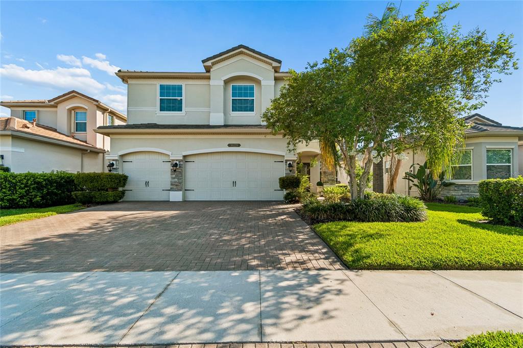 A two-story suburban house features a paved driveway, a three-car garage, and a front lawn — 30229 SOUTHERNWOOD COURT, WESLEY CHAPEL, FL