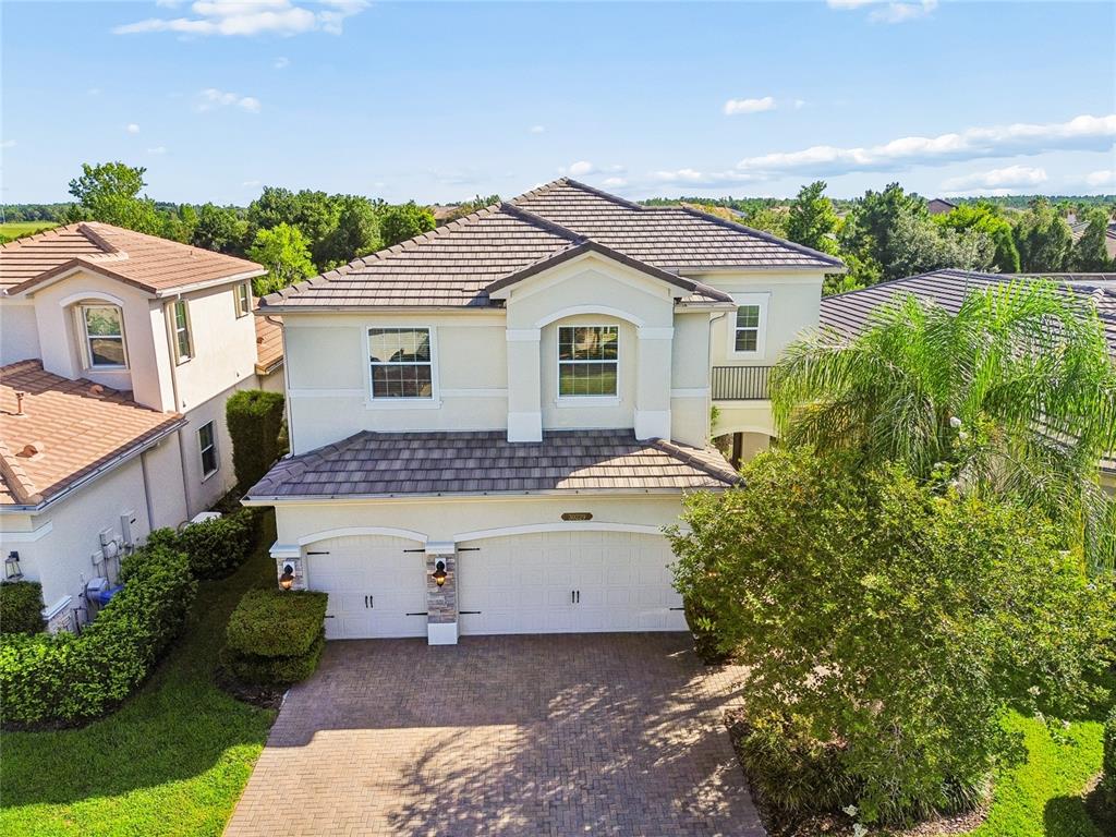 A two-story suburban house features a tiled roof, stucco exterior, and a three-car garage — 30229 SOUTHERNWOOD COURT, WESLEY CHAPEL, FL