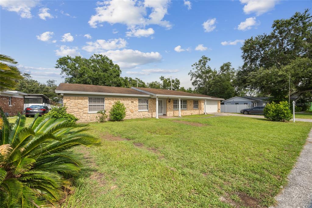 A single-story house with a stone facade and a large front lawn under a blue sky — 409 DEBRA DRIVE, BRANDON, FL