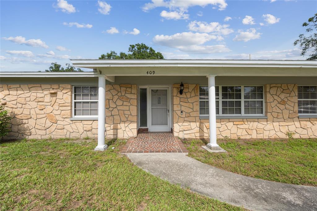 A single-story house exterior features a stone facade, white columns, and a front entryway — 409 DEBRA DRIVE, BRANDON, FL