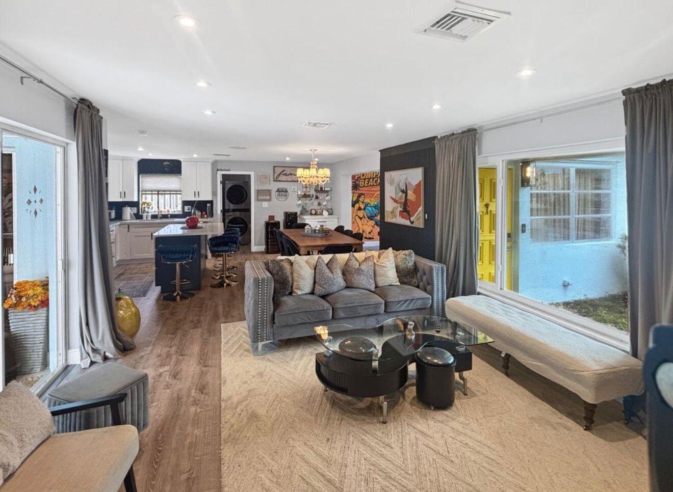 An open-concept living room and kitchen featuring a gray sofa, glass coffee table, and island — 100 SW 17th Street, Pompano Beach FL 33060, POMPANO BEACH, FL