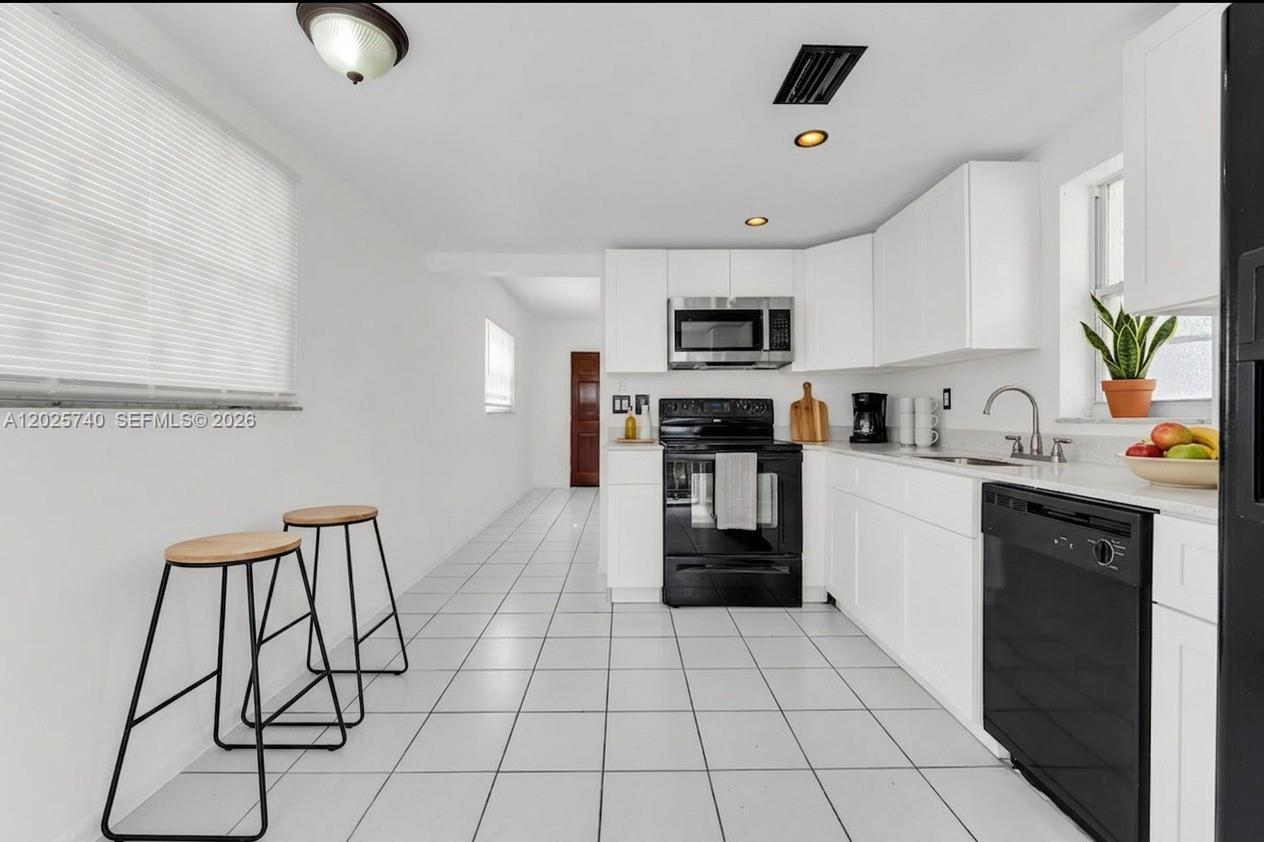 A kitchen features white cabinets, black appliances, white tile flooring, and a breakfast bar area — 321 SW 1st Ct # 4, Pompano Beach FL 33060, POMPANO BEACH, FL