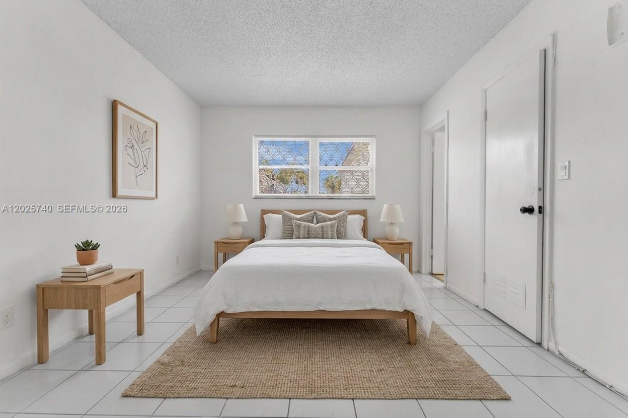 A bedroom features a bed with white bedding, two nightstands, and white tiled flooring — 321 SW 1st Ct # 4, Pompano Beach FL 33060, POMPANO BEACH, FL