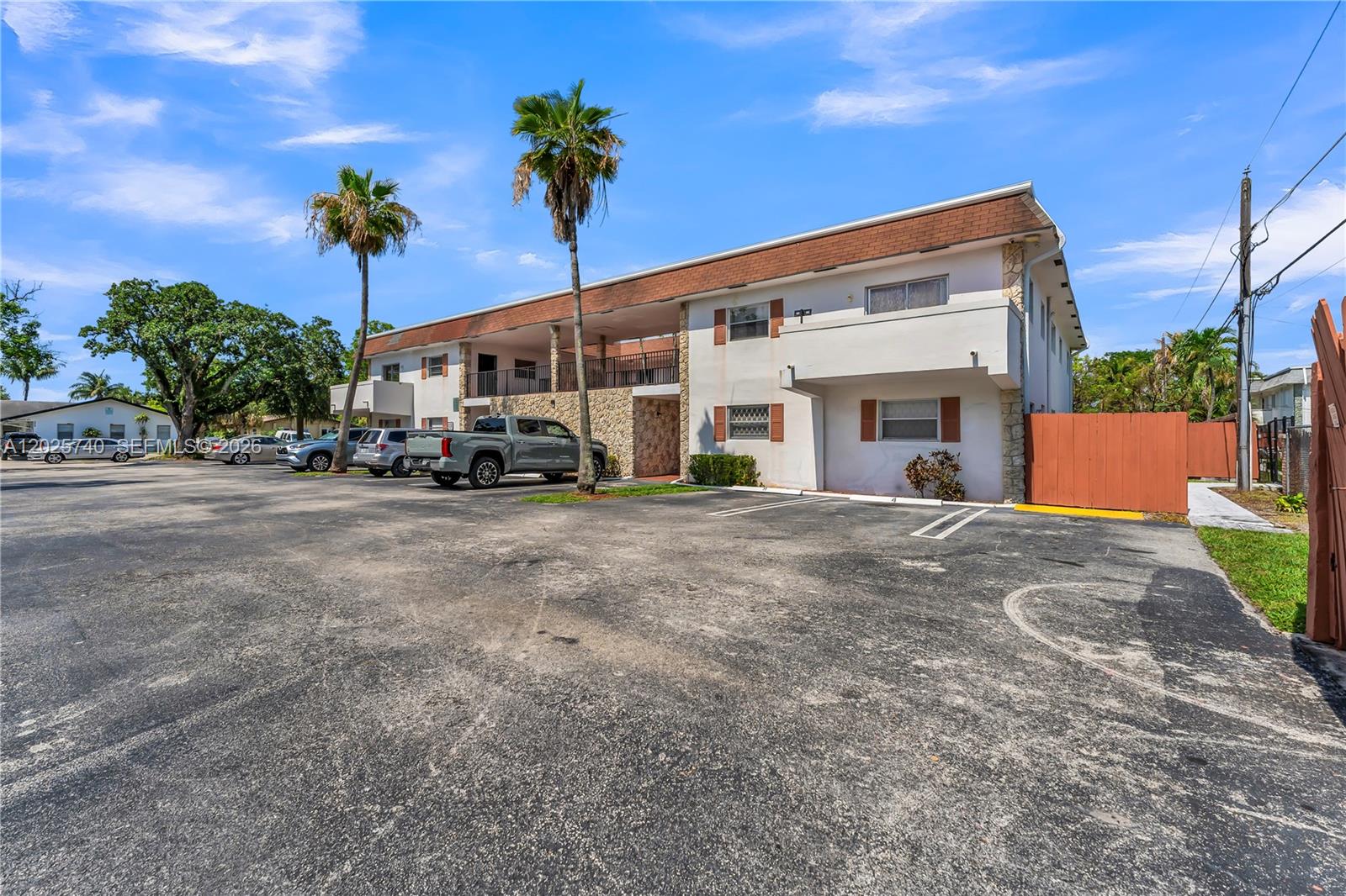 A two-story apartment building features a paved parking lot, palm trees, and a wooden fence — 321 SW 1st Ct # 4, Pompano Beach FL 33060, POMPANO BEACH, FL
