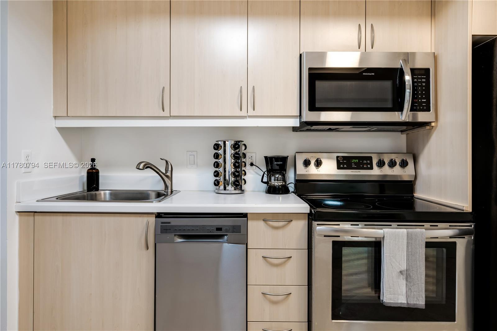 A kitchen features light wood cabinets, stainless steel appliances, and a white countertop — 2951 S Bayshore Dr # 815, Miami FL 33133, MIAMI, FL