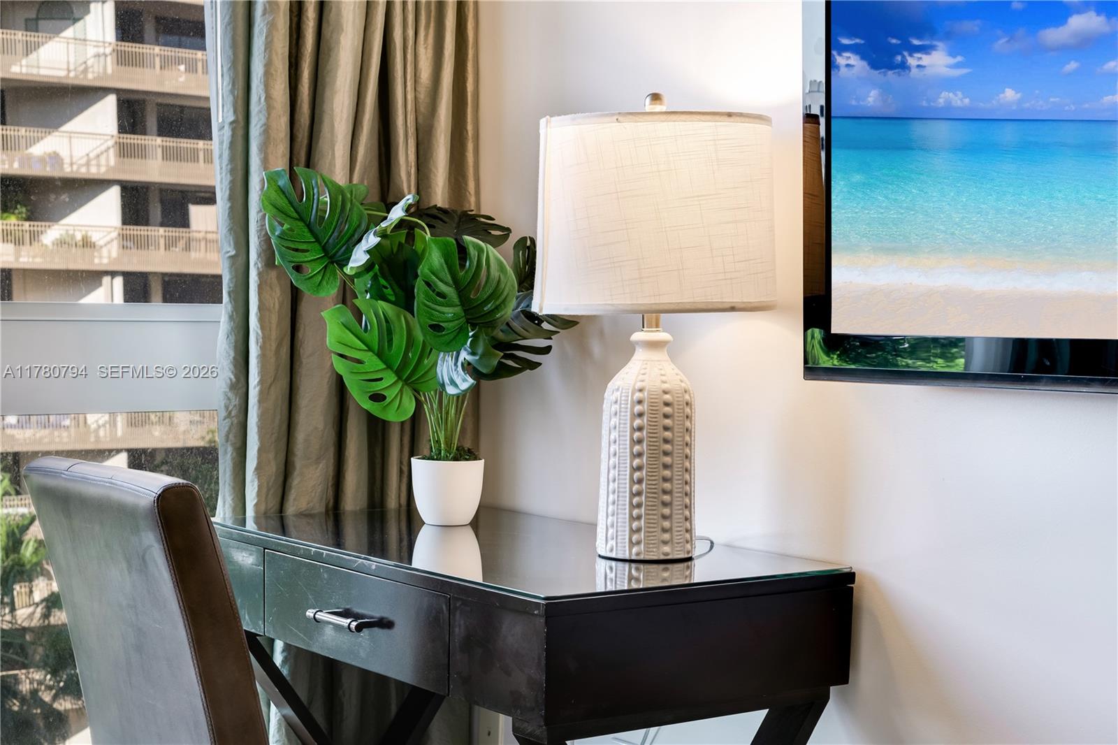 A desk with a lamp and a potted plant sits near a window and television — 2951 S Bayshore Dr # 815, Miami FL 33133, MIAMI, FL