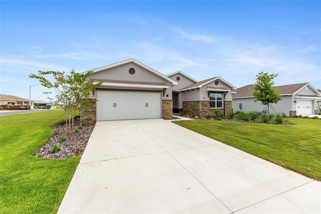 A single-story suburban house features a two-car garage, stone accents, and a concrete driveway — 10119 SW 106TH CIRCLE, OCALA, FL