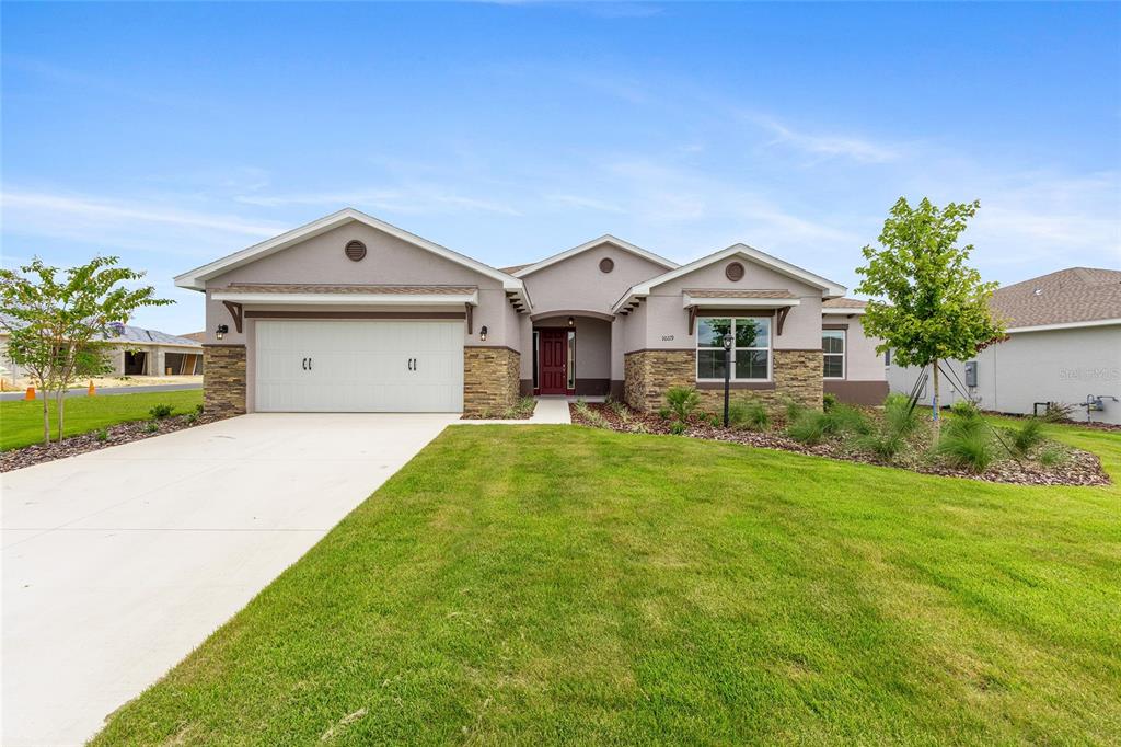 A single-story house with a two-car garage, stone accents, and a red front door — 10119 SW 106TH CIRCLE, OCALA, FL