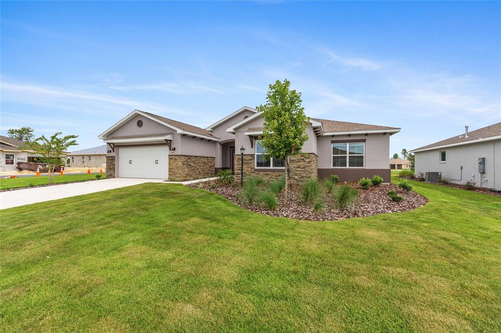 A single-story house with a two-car garage, stone accents, and a landscaped front yard — 10119 SW 106TH CIRCLE, OCALA, FL