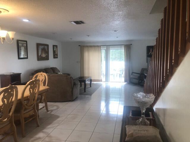 A living and dining area with tile floors, a wooden staircase, and sliding glass doors — 22065 Las Brisas Circle # 401, Boca Raton FL 33433, BOCA RATON, FL