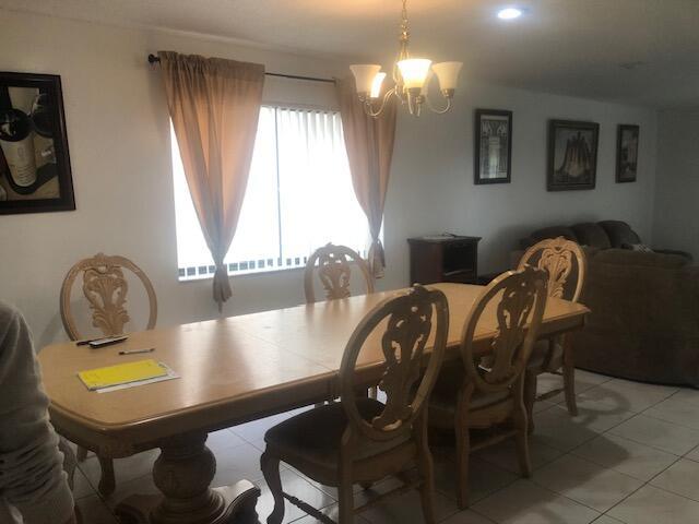 A dining room with a wooden table, four chairs, a chandelier, and tile flooring — 22065 Las Brisas Circle # 401, Boca Raton FL 33433, BOCA RATON, FL