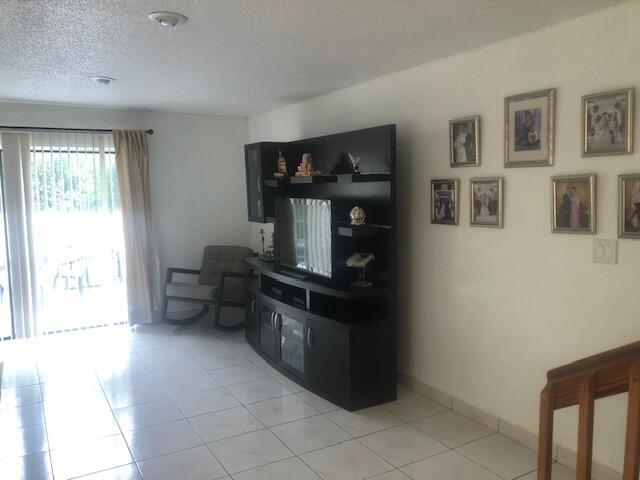 A living room features white tiled floors, a dark entertainment center, and a rocking chair — 22065 Las Brisas Circle # 401, Boca Raton FL 33433, BOCA RATON, FL