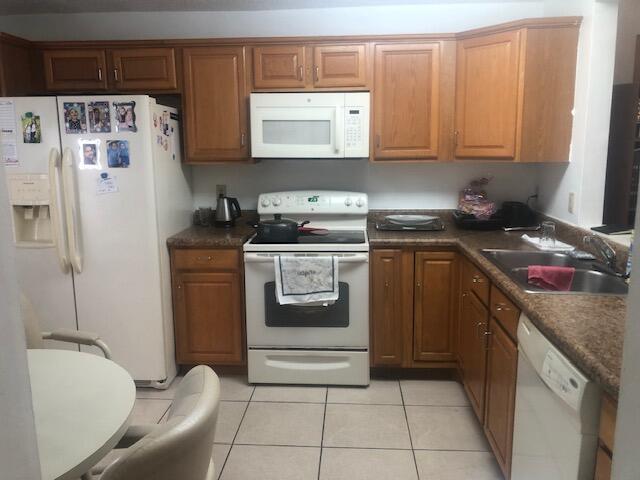 A kitchen features wood cabinets, white appliances, a tiled floor, and a small dining table — 22065 Las Brisas Circle # 401, Boca Raton FL 33433, BOCA RATON, FL