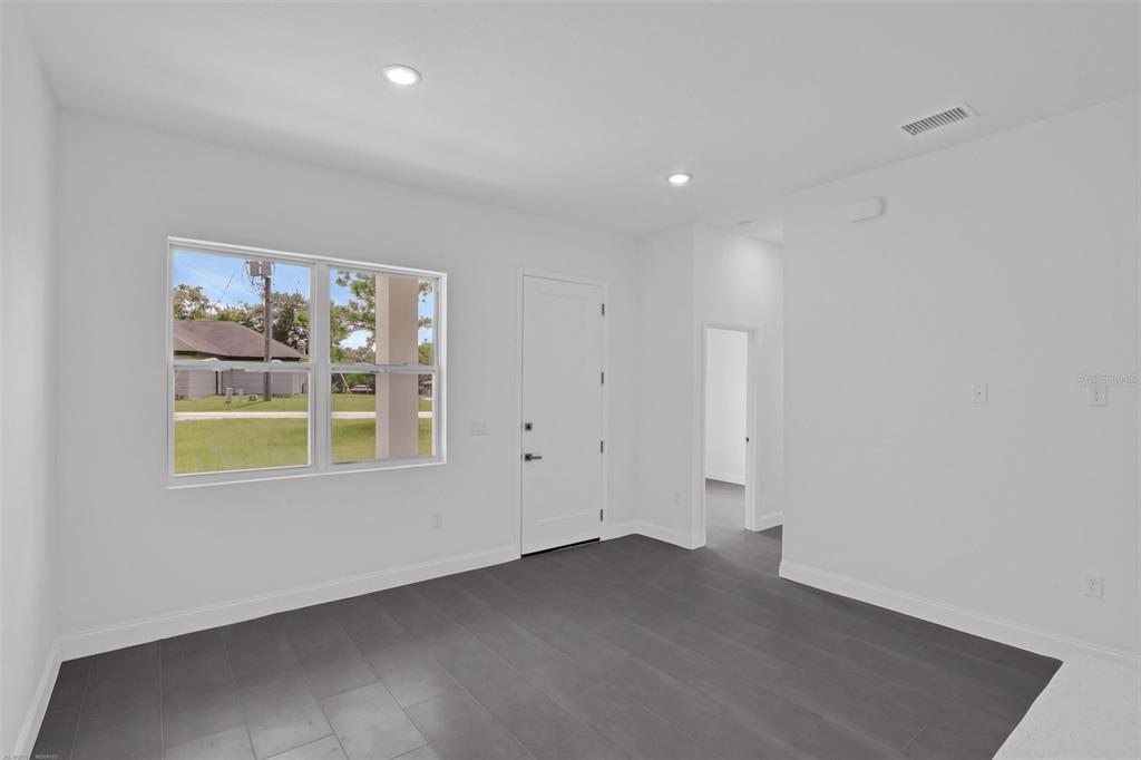 A room with gray tile flooring, white walls, a window, and a white door — 21723 SW BEACH BOULEVARD UNIT 1, DUNNELLON, FL