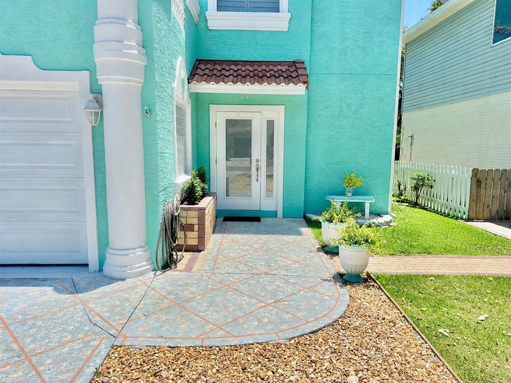 The exterior of a teal house features a white front door, a column, and pavers — 107 6TH STREET N, FLAGLER BEACH, FL