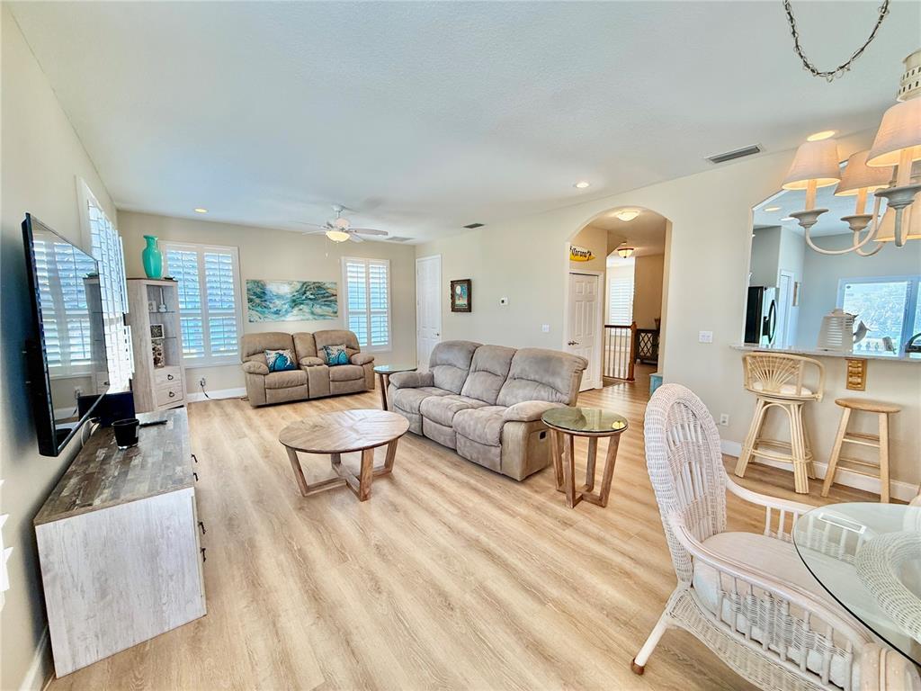 A living room features light wood-look flooring, a beige sofa, and an open kitchen area — 107 6TH STREET N, FLAGLER BEACH, FL