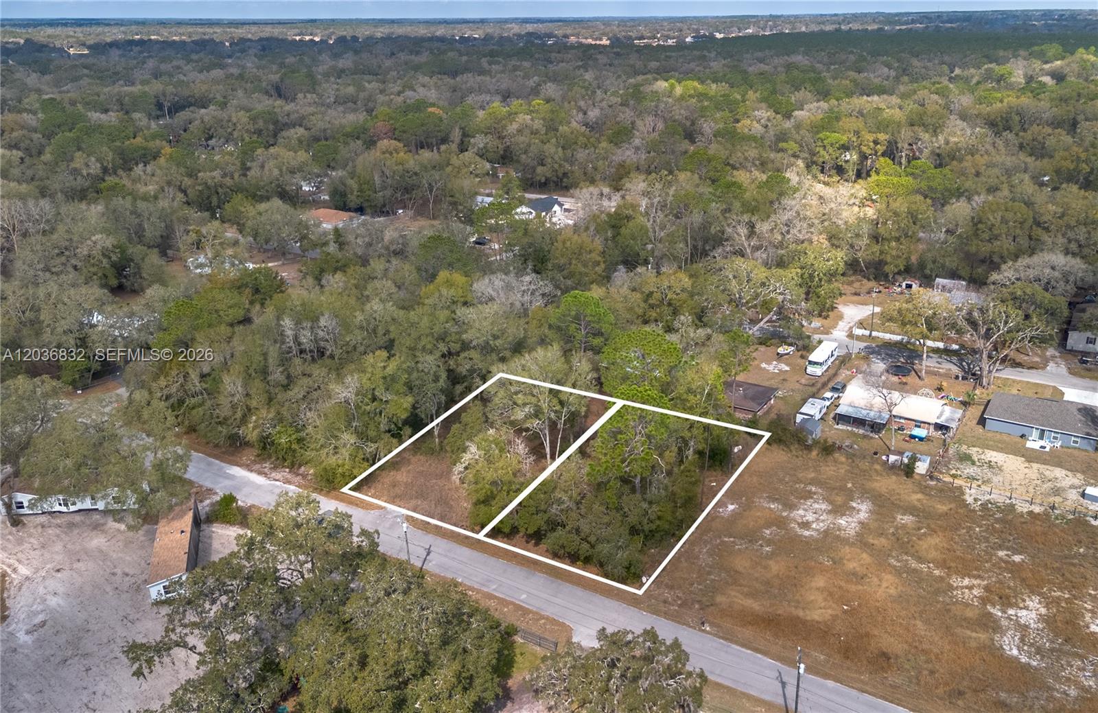 An aerial view shows two adjacent, wooded, rectangular vacant lots bordering a paved road — NW 13th ST, Ocala FL 34482, OCALA, FL