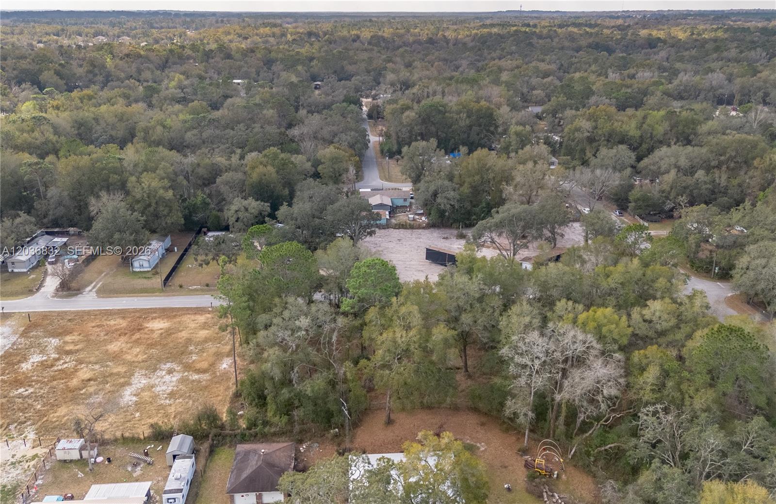 An aerial view shows a rural residential area with scattered houses, cleared lots, and dense trees — NW 13th ST, Ocala FL 34482, OCALA, FL