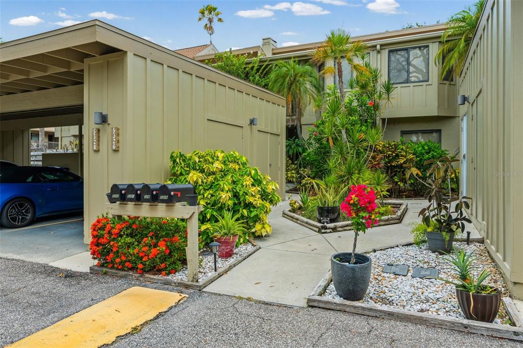 A row of mailboxes sits in front of a tan building with lush landscaping — 5326 LAKE ARROWHEAD TRAIL UNIT 7, SARASOTA, FL