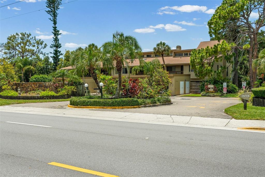 A multi-story apartment building with a landscaped entrance sign and palm trees — 5326 LAKE ARROWHEAD TRAIL UNIT 7, SARASOTA, FL