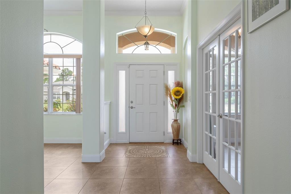A bright entryway features tile flooring, a white front door, and French doors — 7 FLINT HILL LANE, PALM COAST, FL
