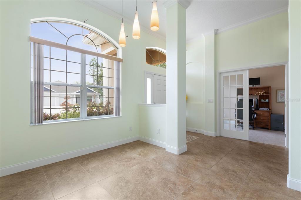 An empty room with tile floors, a large arched window, and French doors leading inside — 7 FLINT HILL LANE, PALM COAST, FL