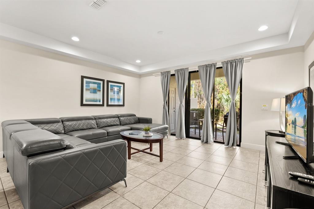 A living room features a grey sectional sofa, tile flooring, and sliding glass patio doors — 8193 ROSEVILLE BOULEVARD, DAVENPORT, FL